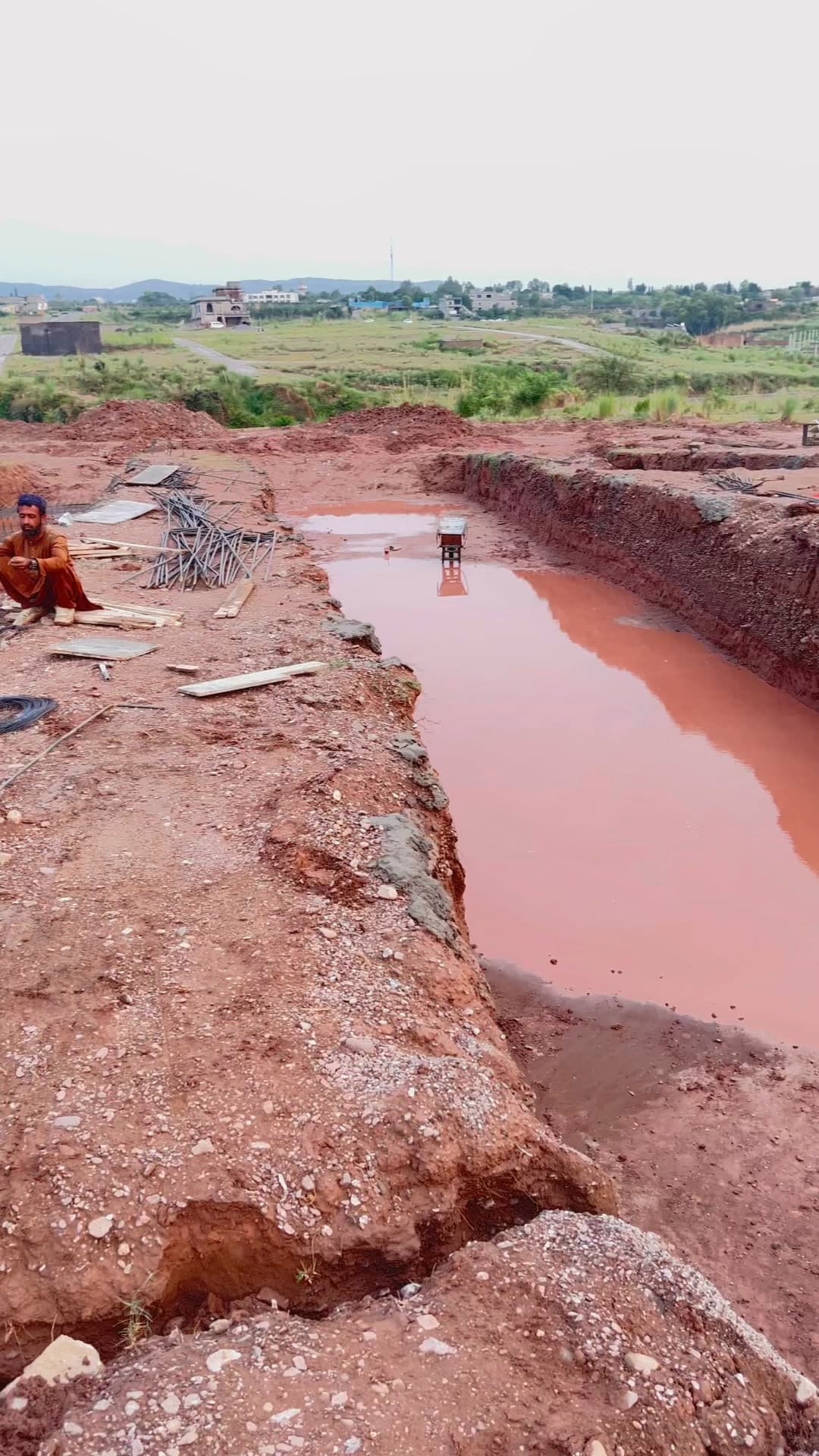 Excavated foundation trenches at the Parsa Home site, filled with rainwater after a storm.